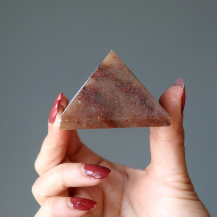 hand holding red aventurine pyramid