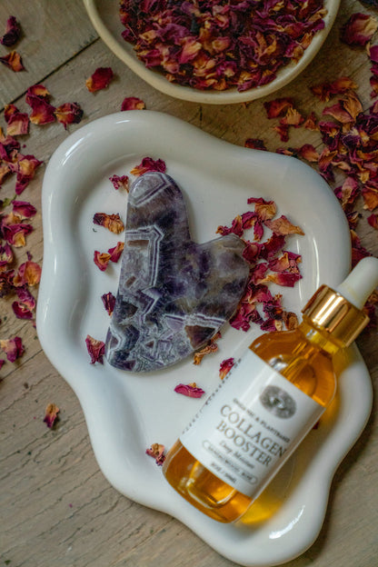 Collagen booster bottle with dropper on a white dish with dried flowers and crystals.
