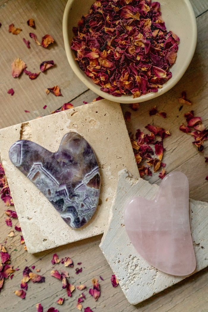 Two crystal tools on a wooden surface with dried flowers and petals.