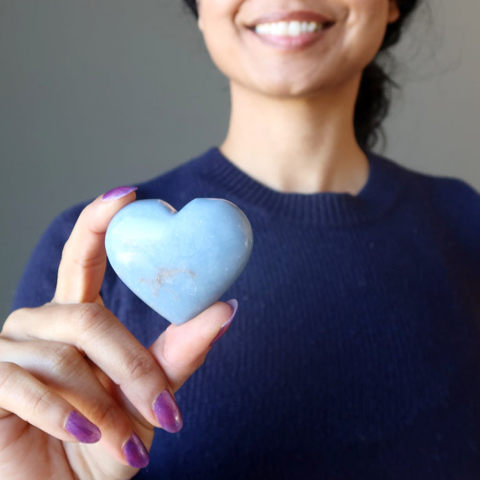 hand holding angelite heart at heart chakra