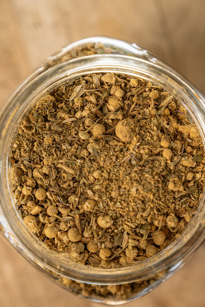 Close-up of a glass jar filled with dried herbs on a wooden surface
