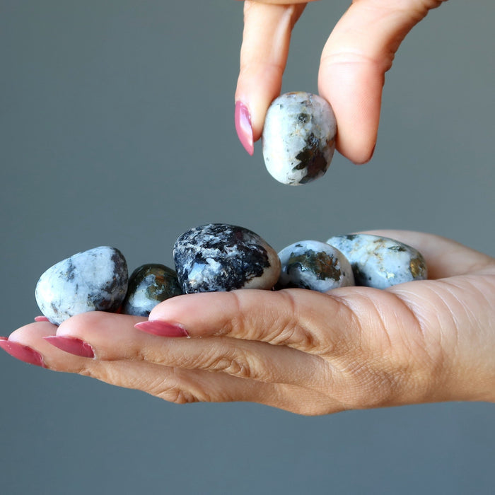 picking one stone from the set of tumbled Snow Quartz Chalcopyrite