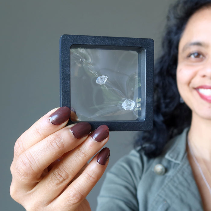 sheila of satin crystals holding 3 Double Terminated Raw Clear Quartz gemstones in zero gravity case