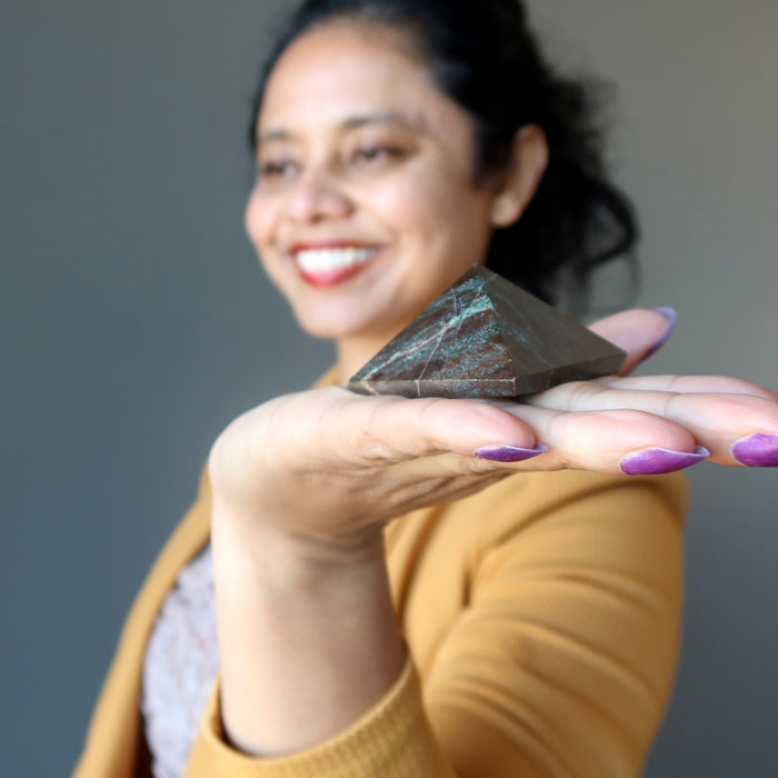 woman holding red garnet pyramid