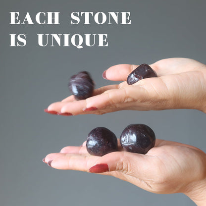 two hands holding pairs of garnet tumbles