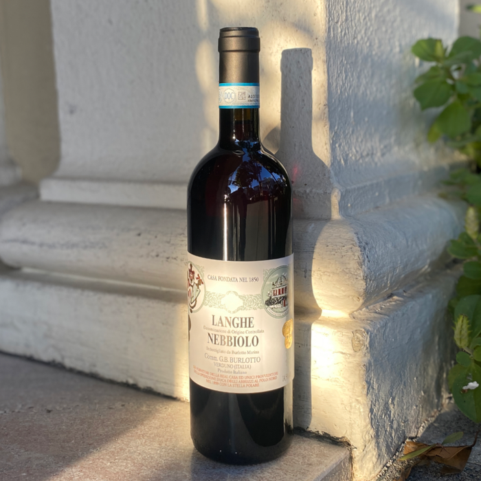 Dark red wine bottle standing with Langhe Nebbiolo label and blue neck band