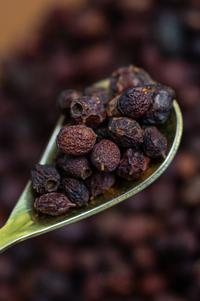 Close-up of a spoonful of dark peppercorns with a blurred background