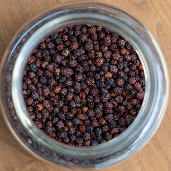 Glass jar filled with dark berries on a wooden surface