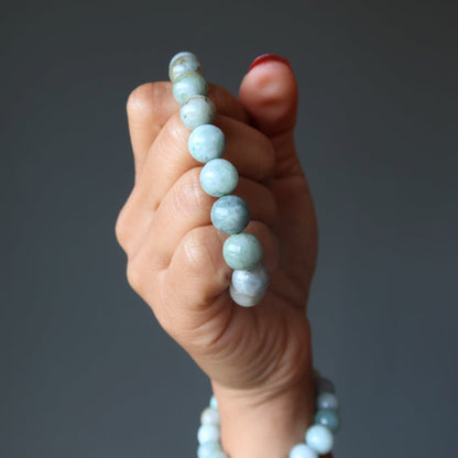 hand holding and wearing green jade bracelets