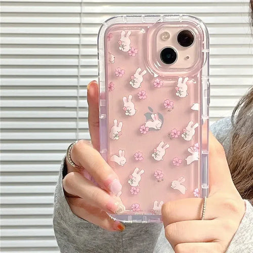 A woman holding a pink phone case with white rabbit and flowers