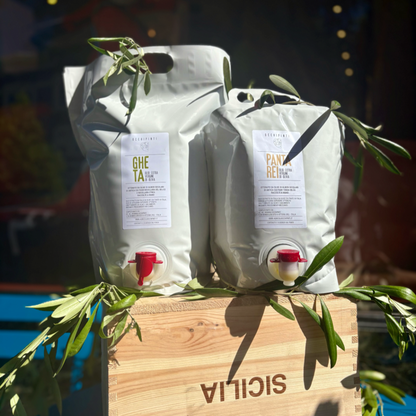 Extra virgin olive oil pouches with red pour spouts on wooden crate