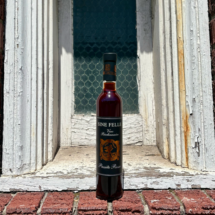 Standing dark red wine bottle with black cap; 'SINE FELLE' label