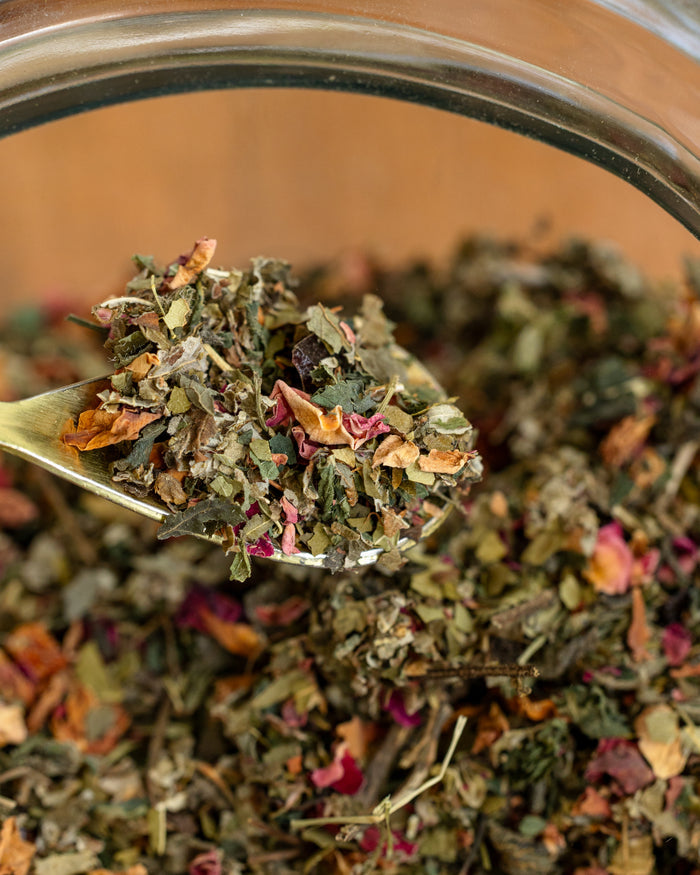 Spoonful of dried herbs and flowers over a jar