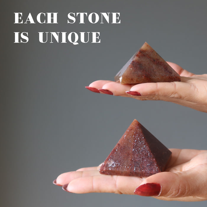 hands holding red aventurine pyramids to show each is unique