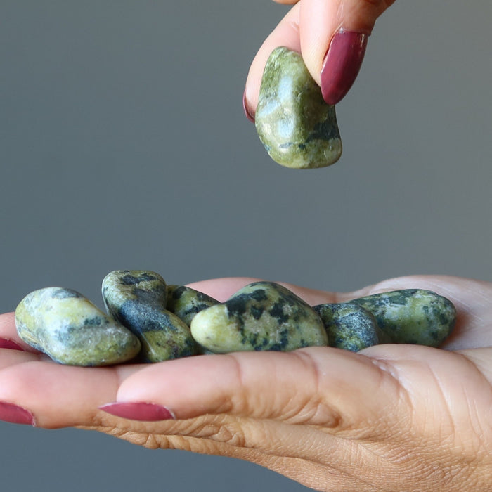 model picking one of many Serpentine Tumbled Stones from the other hand