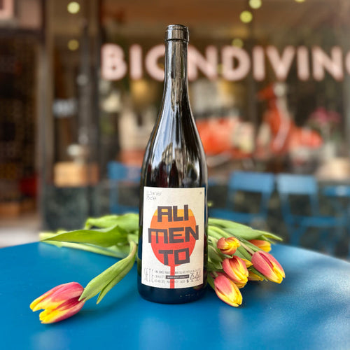 2023 white wine bottle with printed label, surrounded by tulips on table