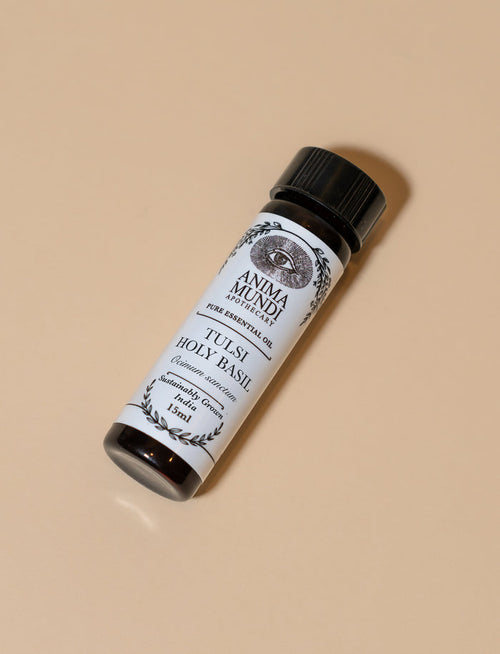 Small bottle of Tuisi Holy Basil oil with a black cap on a beige background